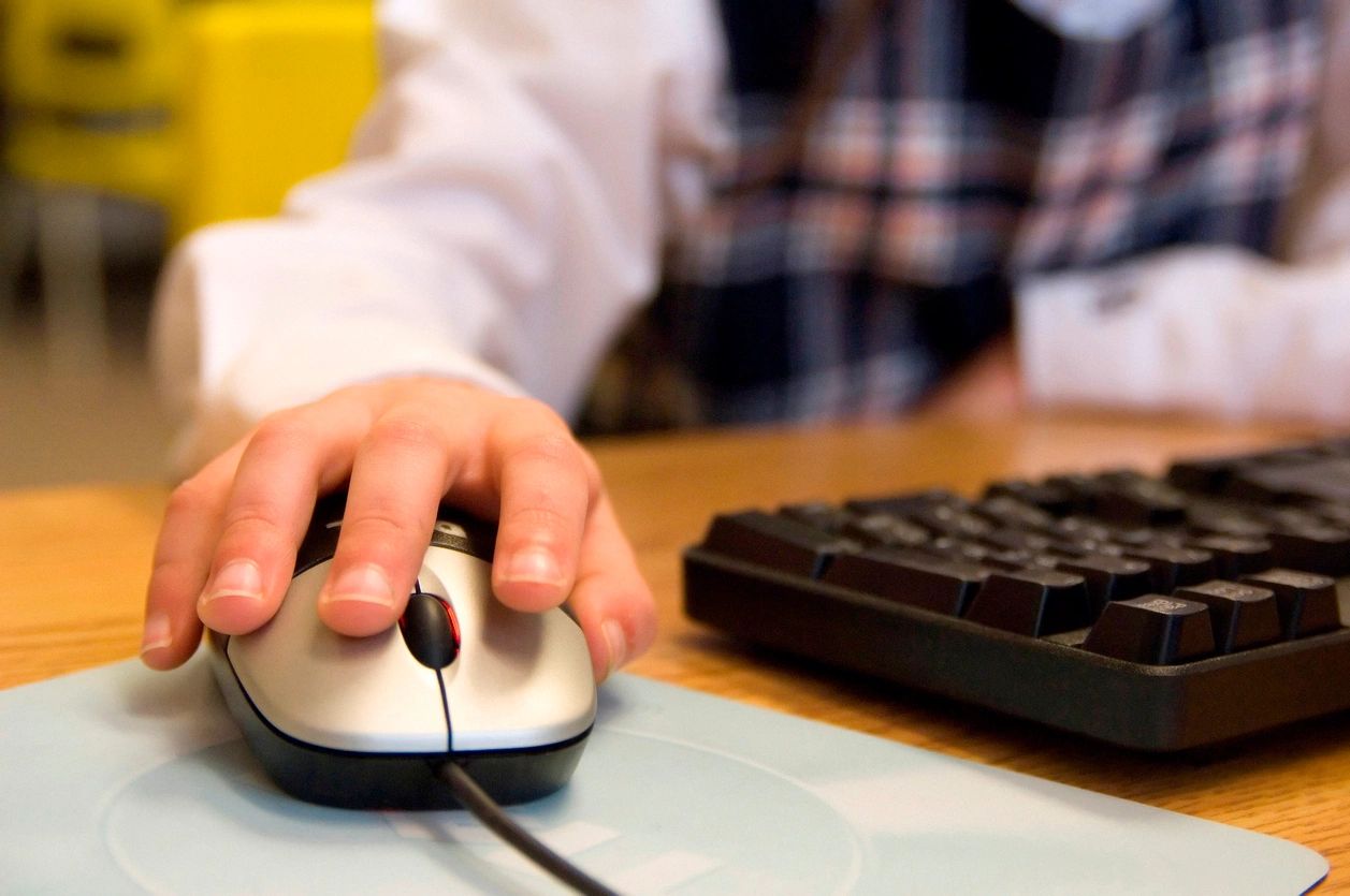 Child using wired computer mouse and keyboard