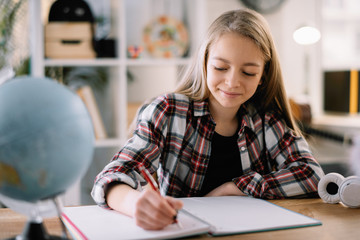 Teen girl studying at desk with globe